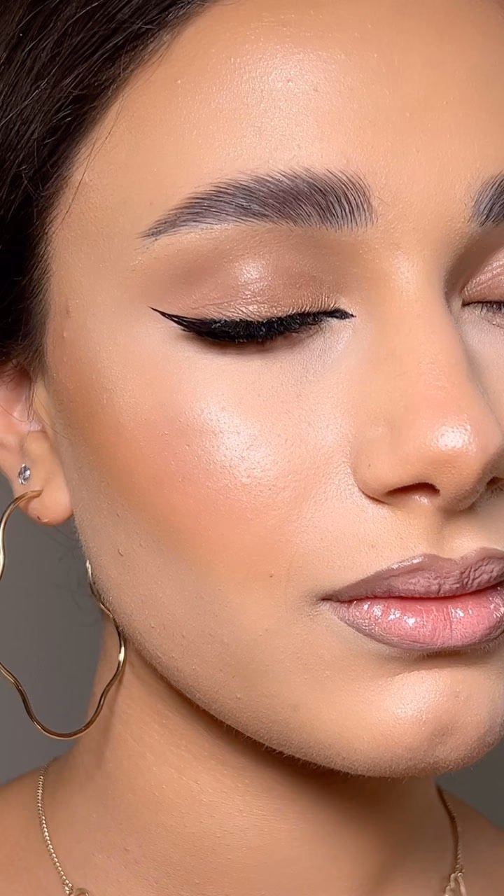 Close-up of a sharp black winged liner with luminous skin, brushed brows and a glossy nude lip